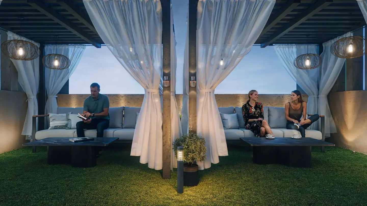 Rooftop cabana lounge at dusk with drapes and lantern lighting